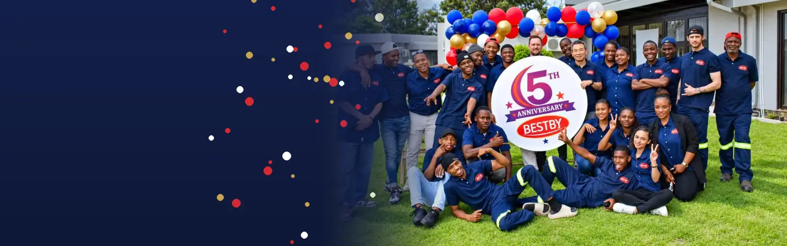 The Bestby team in navy uniforms celebrating the 5th anniversary with a balloon arch and anniversary sign